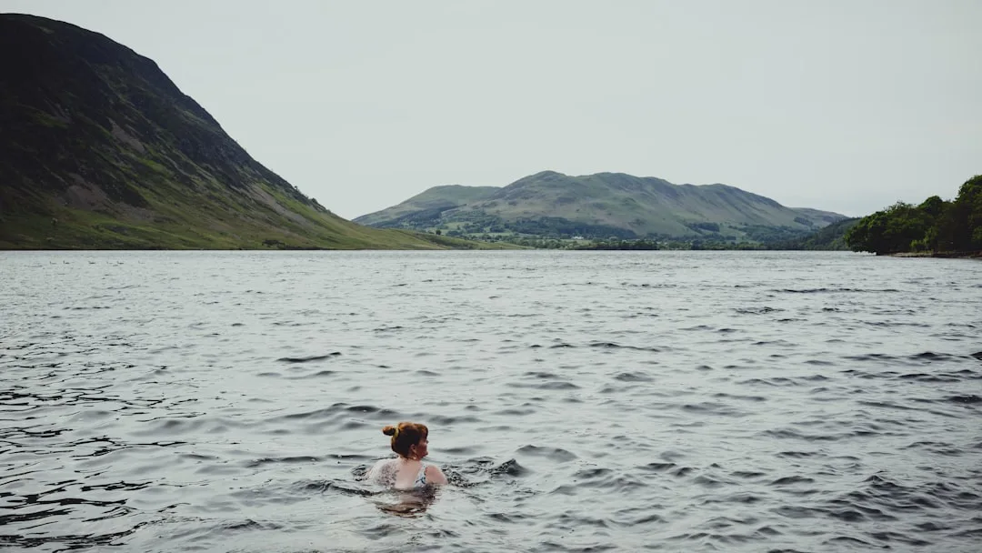 Foto: Jaz Blakeston-Petch / unsplash a woman swimming in a lake with mountains in the background