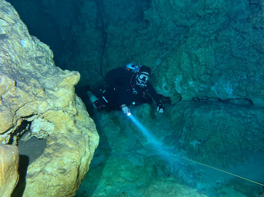 Foto: Francisco Davids / pexels A scuba diver explores the depths of an underwater cave with a flashlight.