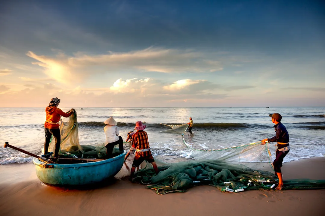 Foto: Quang Nguyen Vinh / unsplash a group of people standing on top of a beach next to a boat